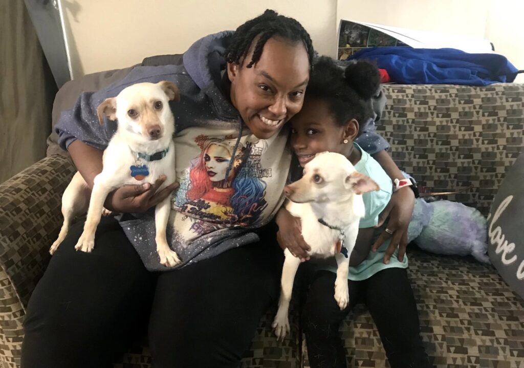 Mujer con su hija y dos perros sobre sofa