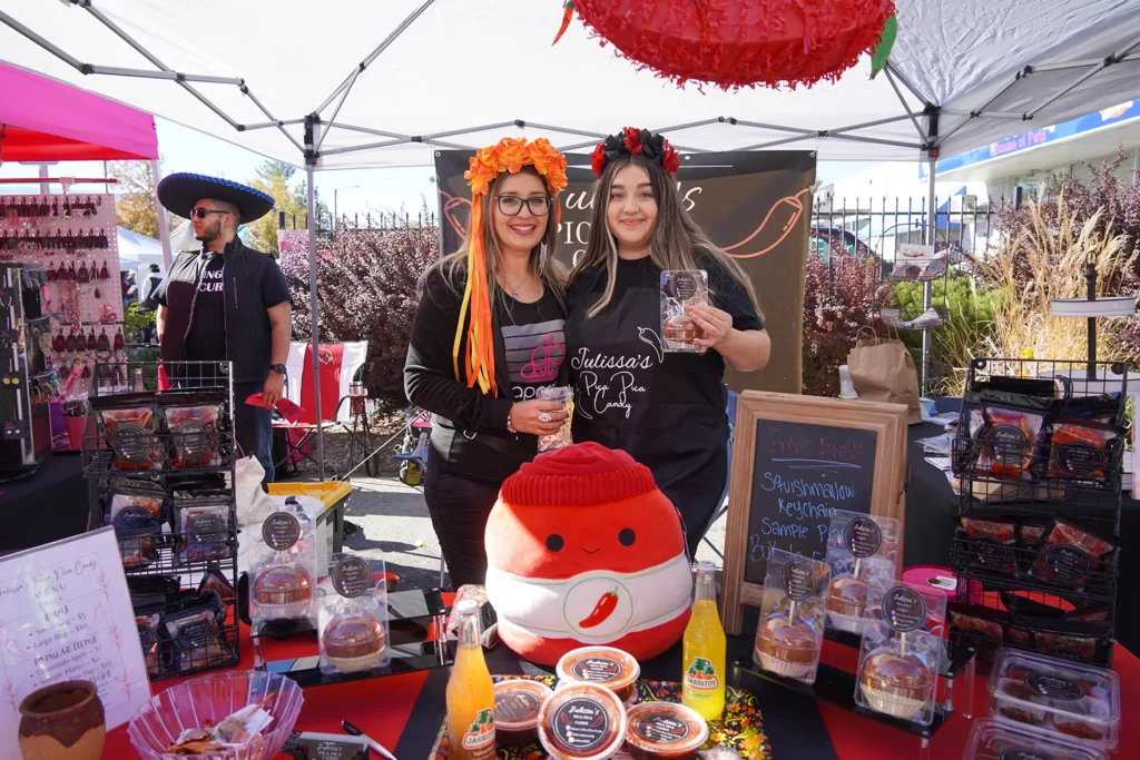 En la foto, dos mujeres sostienen dulces picantes en un puesto de vendedores.