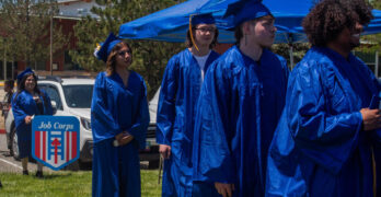 Los estudiantes graduados, vestidos con túnicas azules, caminando hacia la ceremonia.