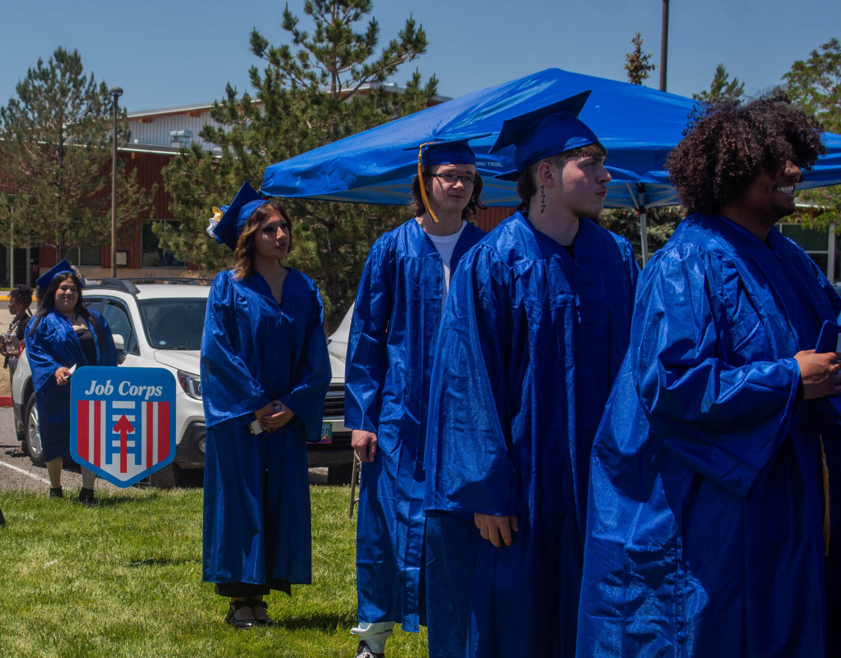 Los estudiantes graduados, vestidos con túnicas azules, caminando hacia la ceremonia.
