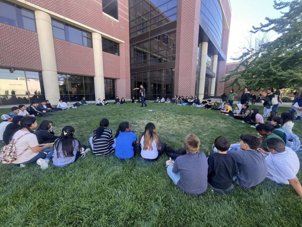 niños sentados en un círculo en el exterior de un edifico