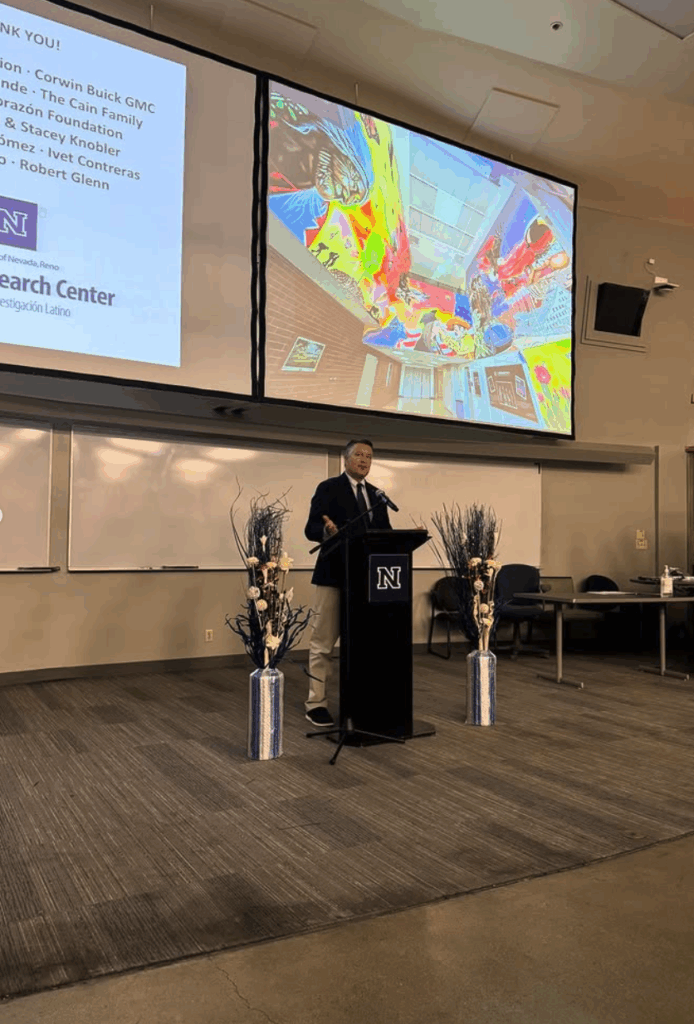 Hombre hablando en un podio en una gran sala con pantallas a sus espaldas.