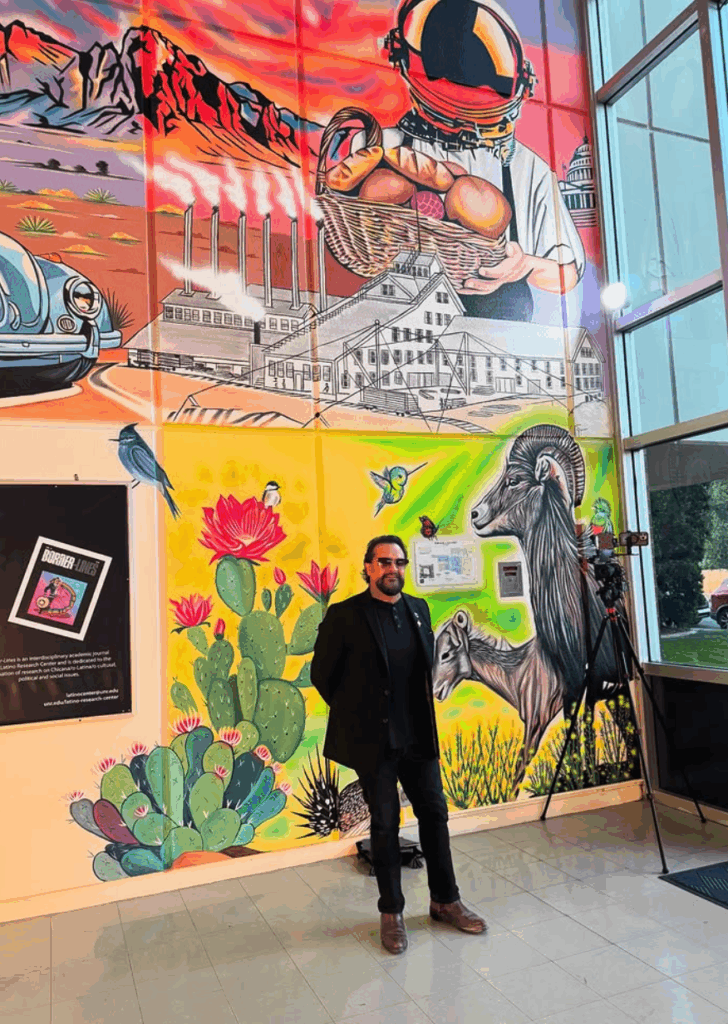 Un hombre está de pie en el pasillo de un edificio frente a un mural.