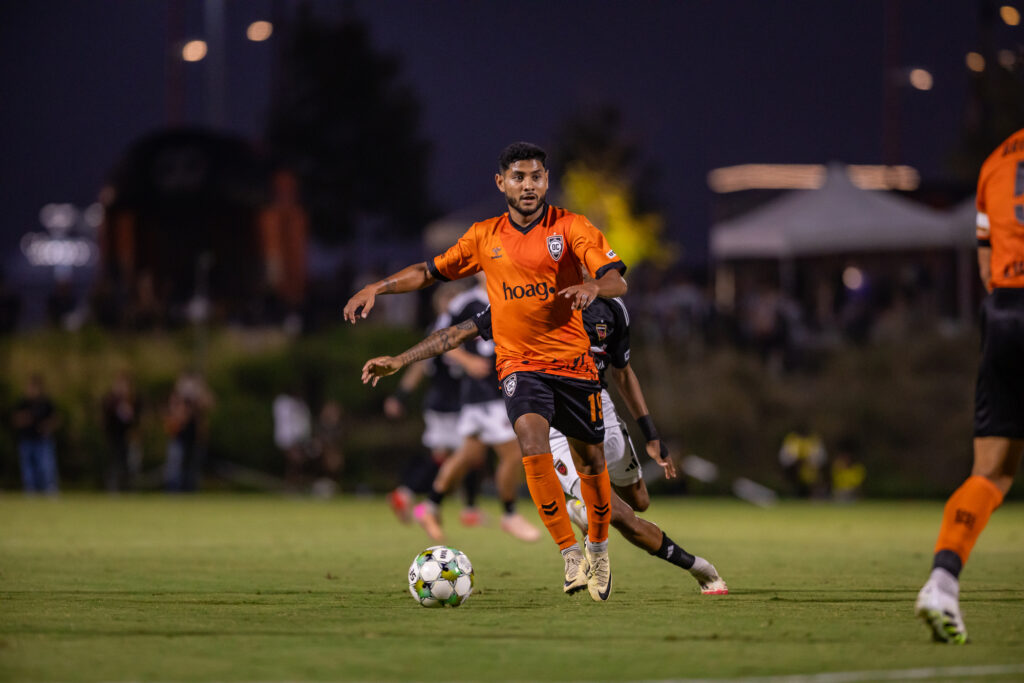 hombre con balón de futbol a sus pies