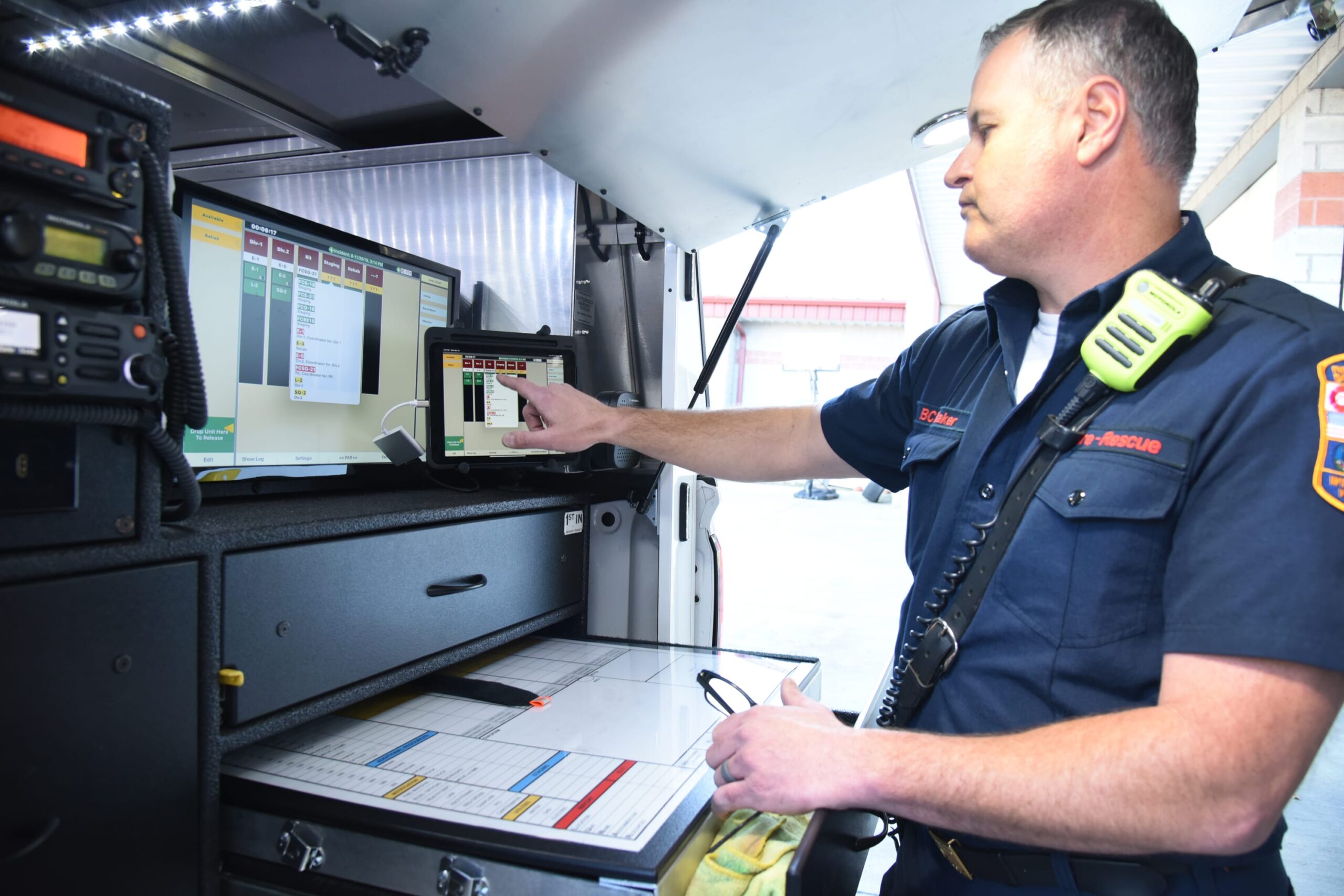 Bombero señalando la información que aparece en un monitor dentro de un camión de bomberos