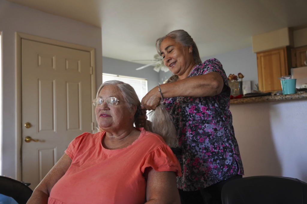 mujer hace trenzas en pelo de una mujer sentada