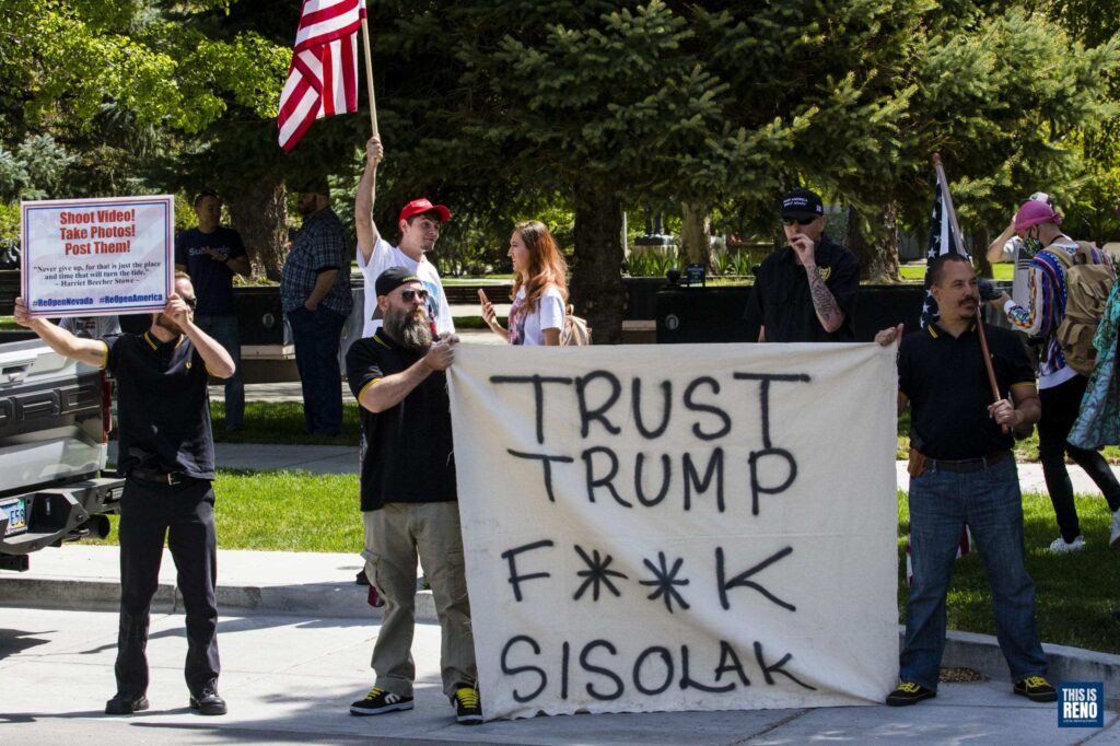 Dos de unas ochos personas en la imagen aguantan letrero con frase "Confíen en Trust"