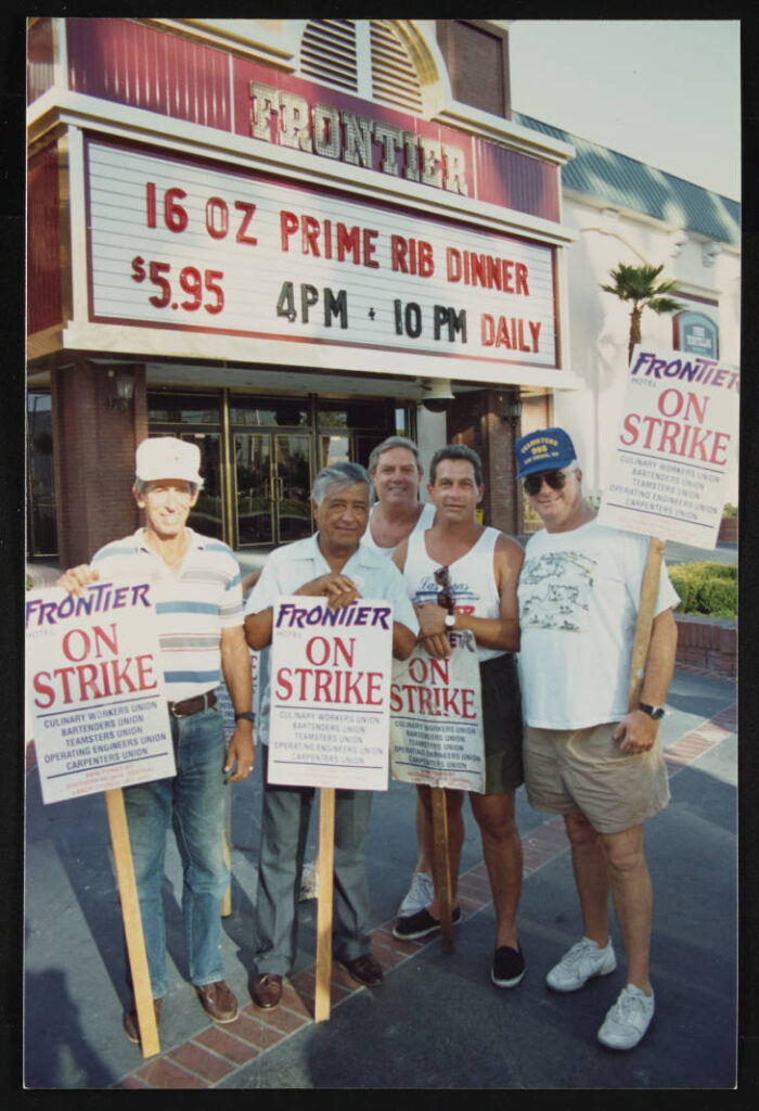 Cinco hombres posan con letreros huelguistas