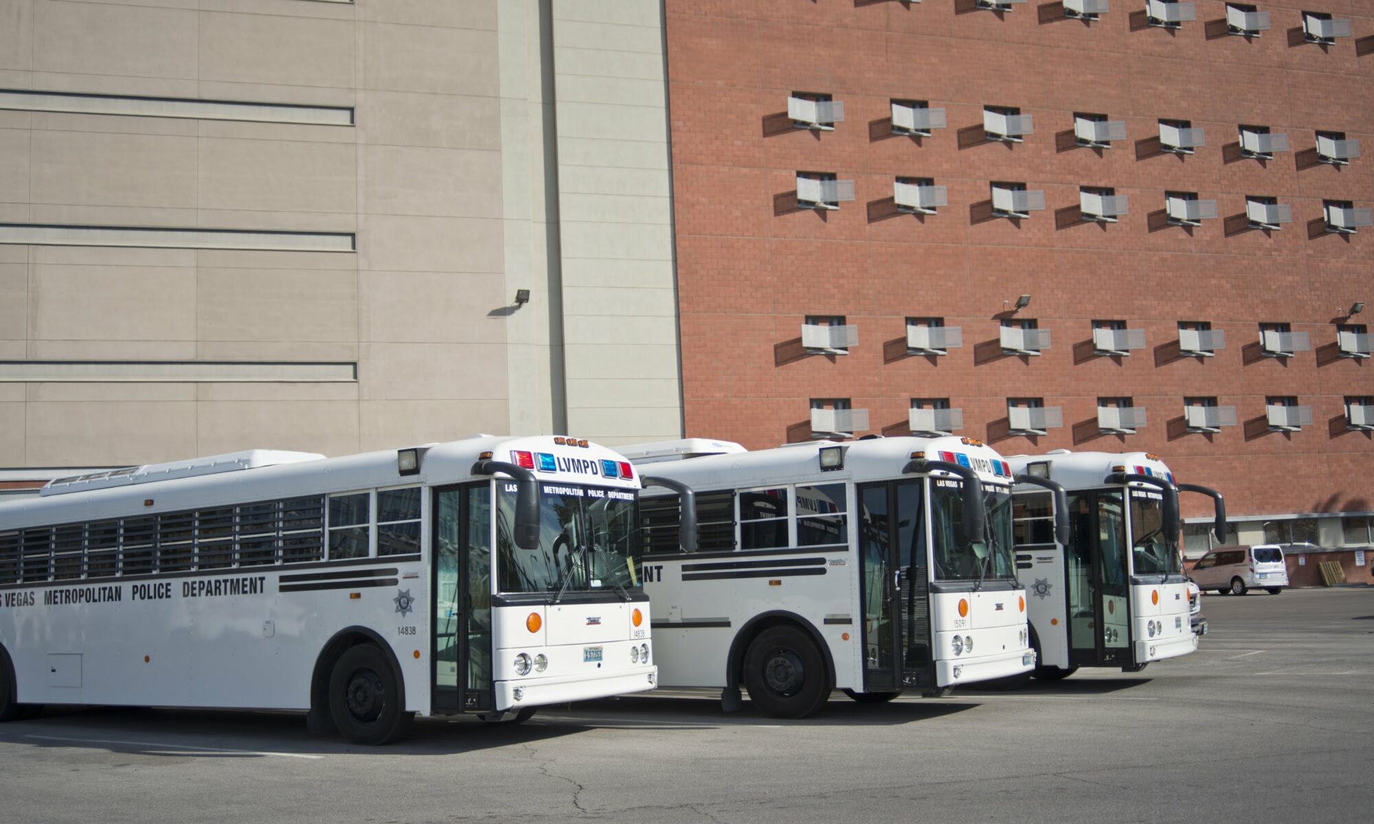 tres buses blancos estacionados afuera de un edificio