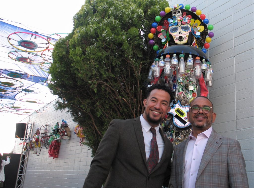 Dos hombres posando con una escultura de reciclaje
