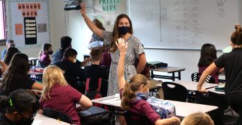 maestra enmascarada con estudiantes enmascarados en una aula