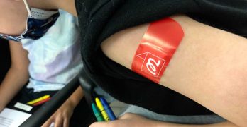 Niño con una curita roja en su brazo