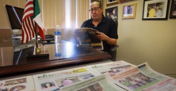 Eddie Escobedo Jr leyendo un periódico detrás de su escritorio