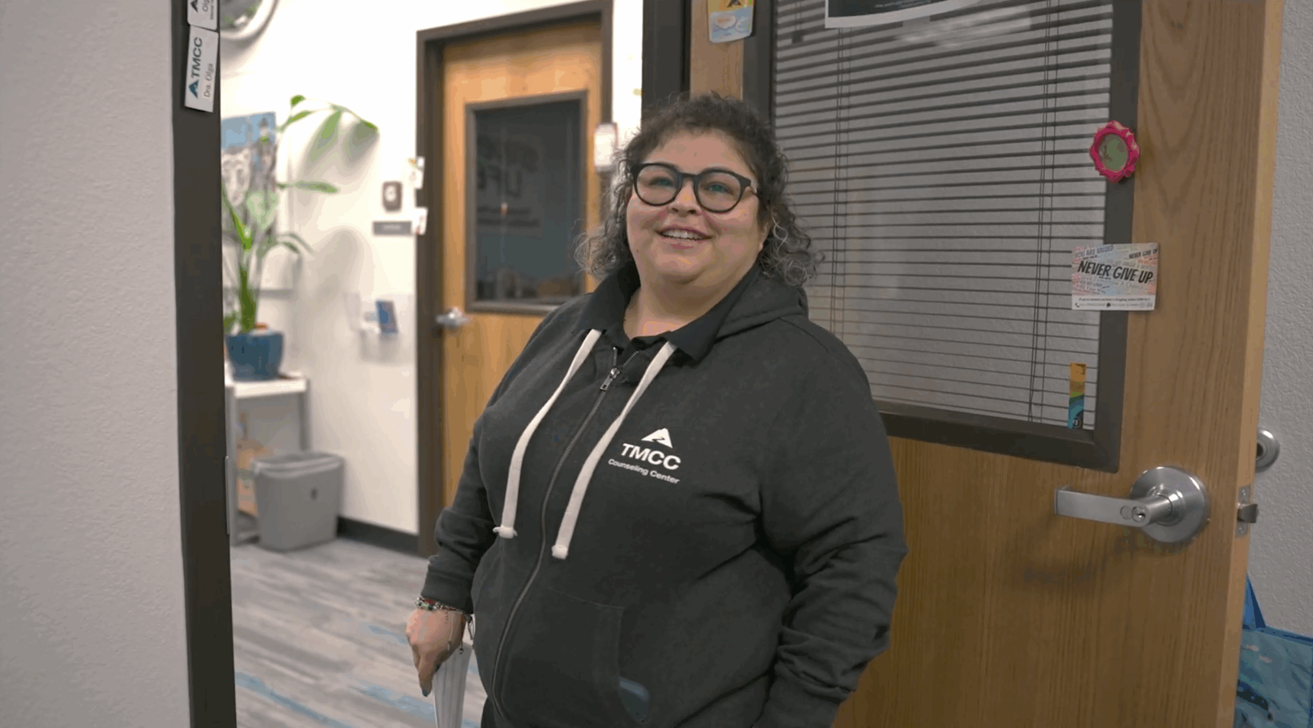 Mujer sonriente de pie en la puerta de una oficina.