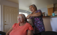 mujer hace trenzas en pelo de una mujer sentada