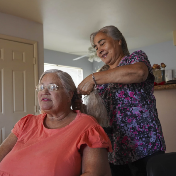 mujer hace trenzas en pelo de una mujer sentada